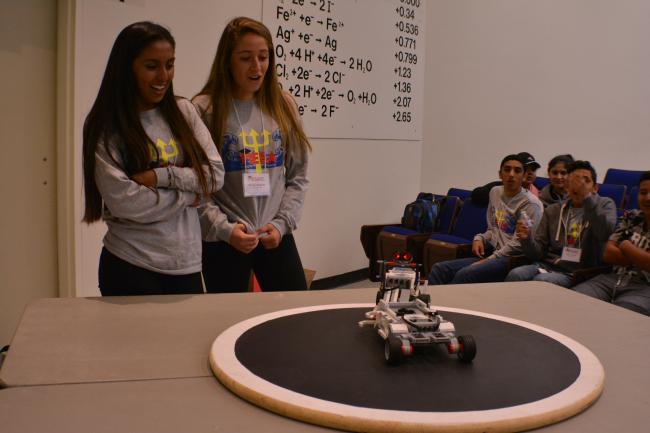 Students watching robotics on a table