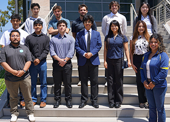 Thirteen people standing on stairs dressed in business casual attire